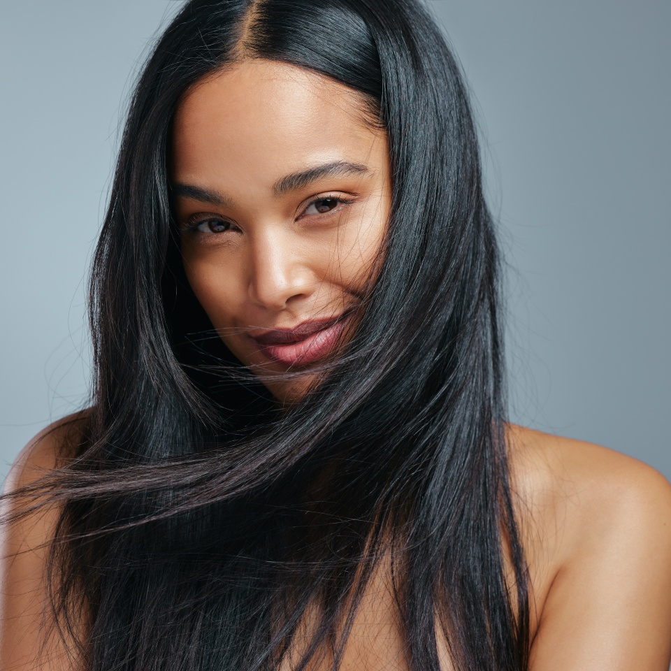 Woman, portrait and hair care in studio with beauty from salon treatment, cosmetics and shampoo shine. Model, person and smile with skincare for wellness, dermatology and glowing on grey background