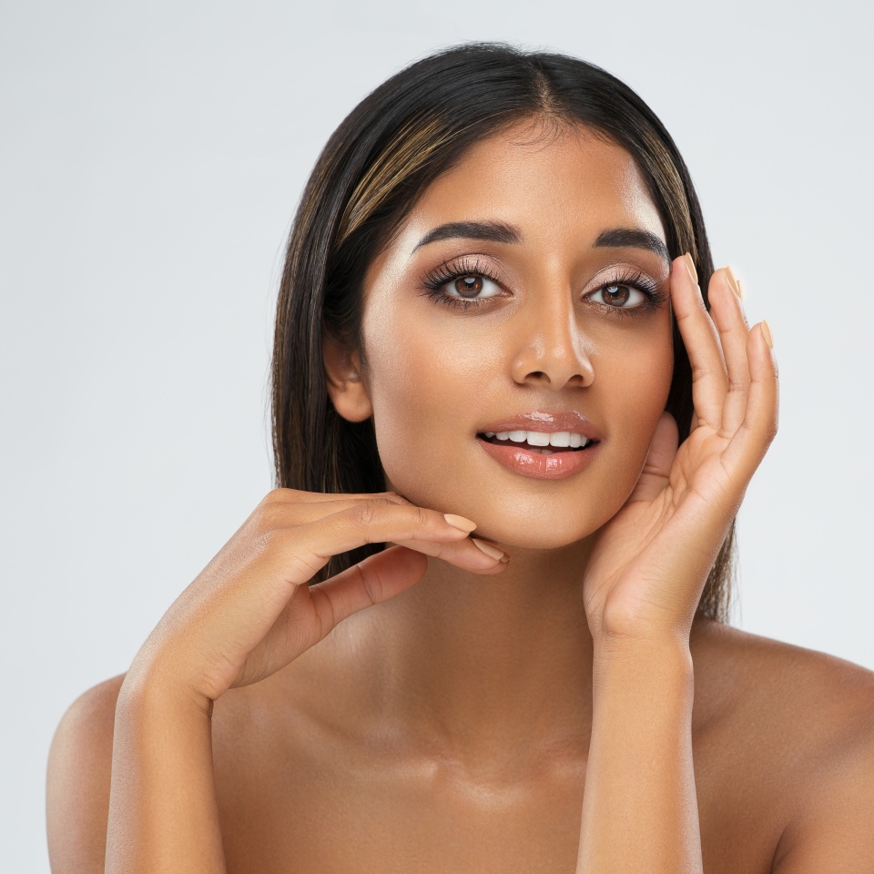 Beautiful Girl Facial Skin Care. Smiling Indian Model with Perfect Eyes Make up isolated White. Women Beauty Spa Cosmetology and Treatment. Face Lift and Dermal Filler Cosmetics