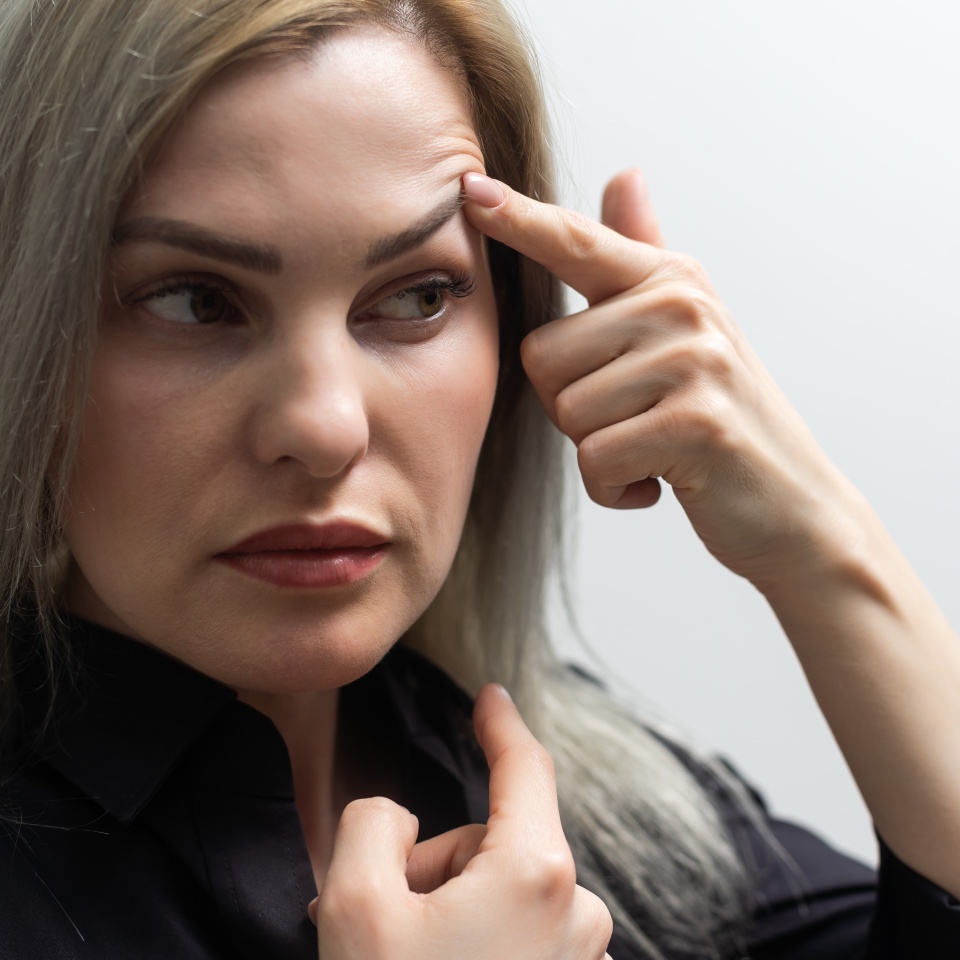 woman shows drooping eyelid for plastic surgery