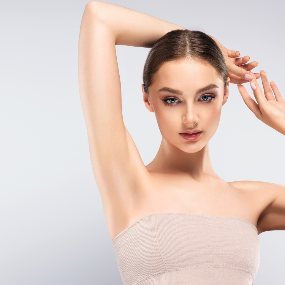 Armpit epilation, lacer hair removal. Young woman holding her arms up and showing clean underarms, depilation smooth clear skin .Beauty portrait.
