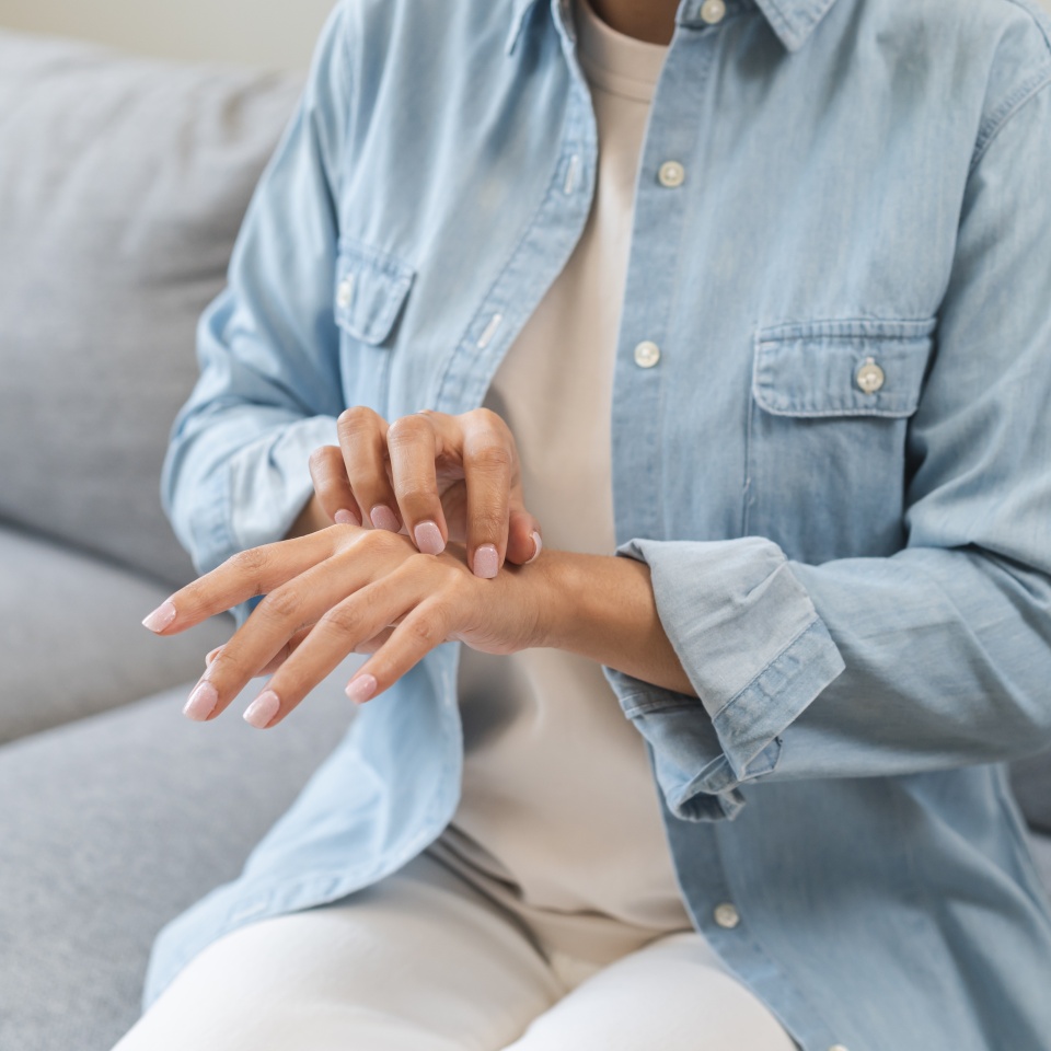 Dermatology, hand pain asian young woman, girl allergy, allergic reaction from atopic, insect bite, scratch itchy back of hand, rash of skin while sitting suffer on sofa at home. Healthcare treatment.